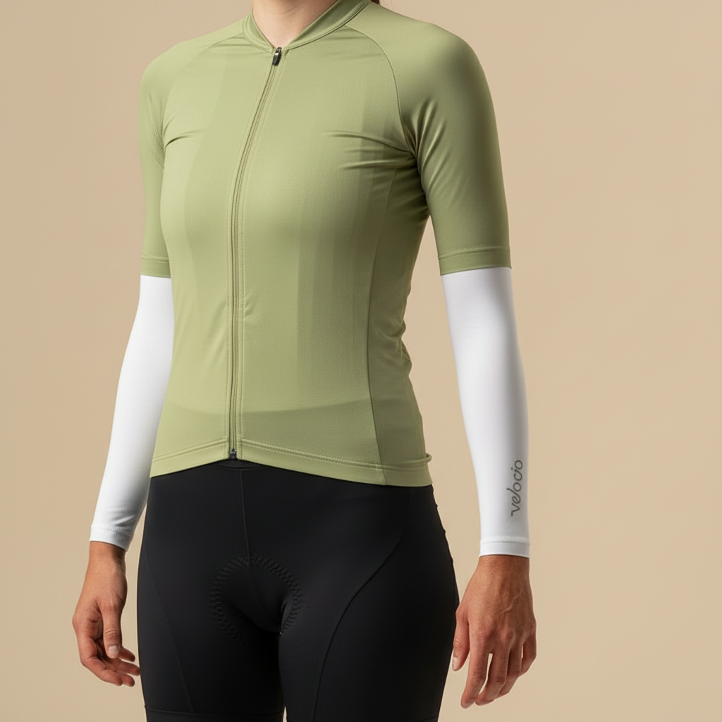 Cycling outfit with green jersey, black shorts, and white arm sleeves on a light yellow background